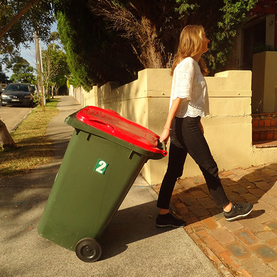 A person bringing in a garbage bin